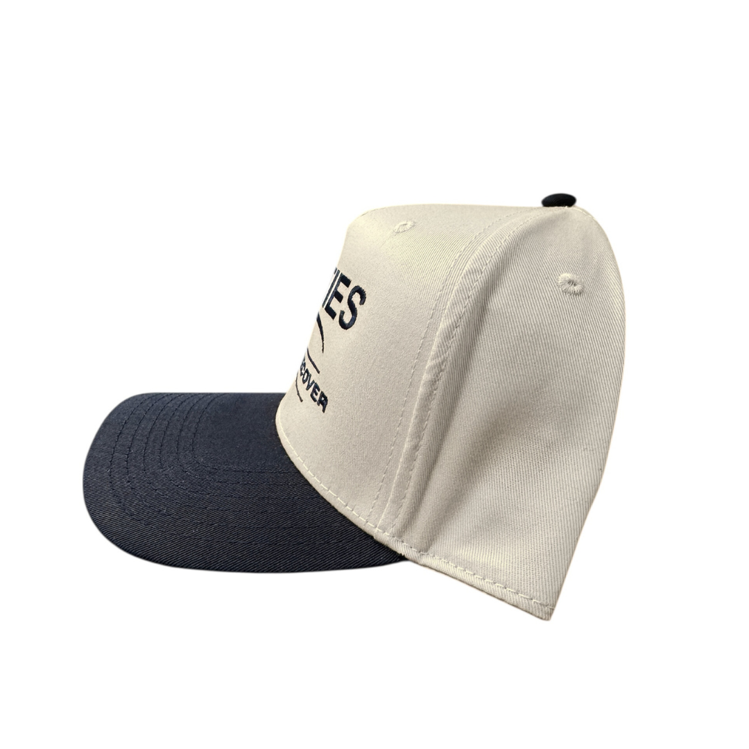JETTIES Relax & Recover snapback hat with navy brim โ structured beige crown and embroidered logo, side view.
