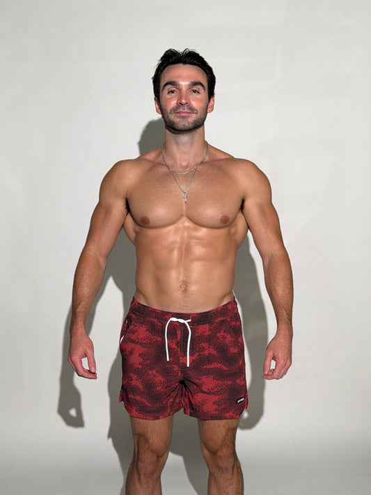 Model wearing the Shadow, black and red digital pixel camo mens bathing suit