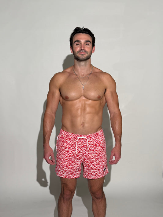 Model wearing the JETTIES Delta Red, red and white triangle mens bathing suit, geometric pattern