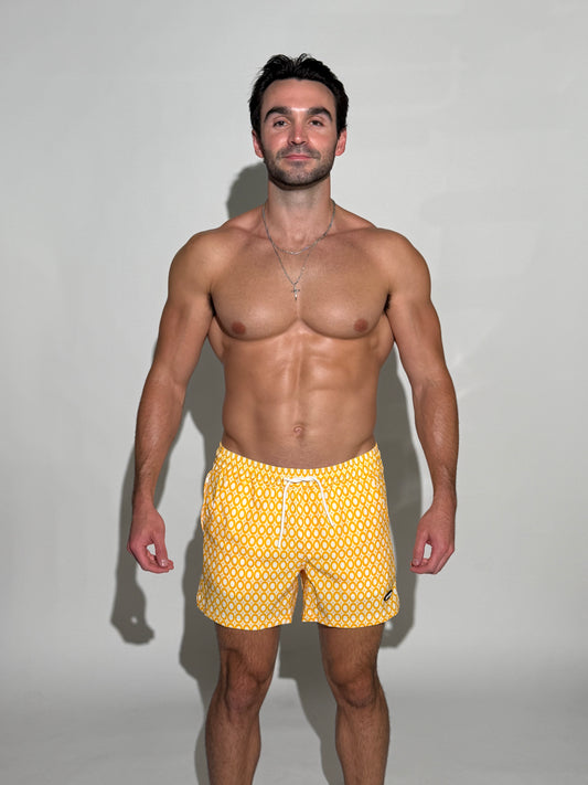 Model wearing the JETTIES Echo Honeycomb, yellow and white circles mens bathing suit, geometric pattern