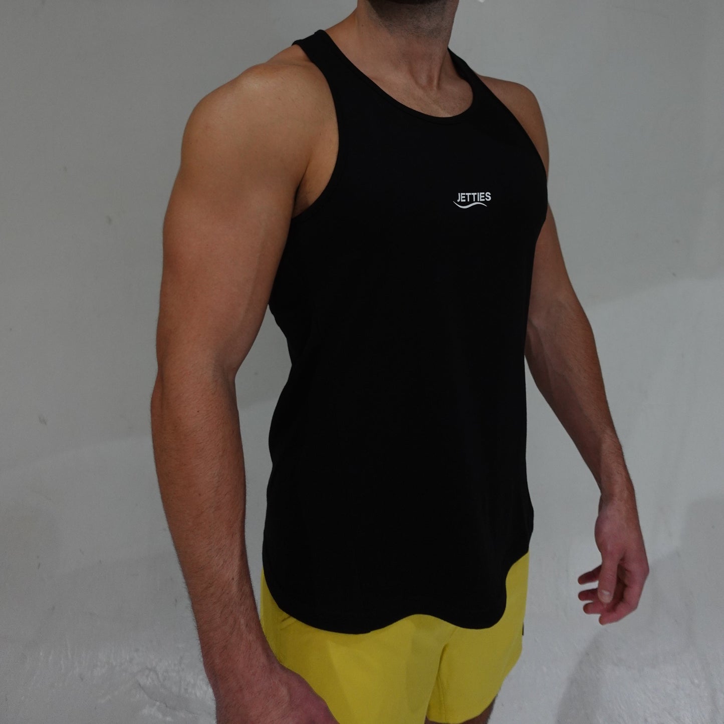 JETTIES Ascend Tank Top in black, lightweight athletic tank with logo graphic, side view