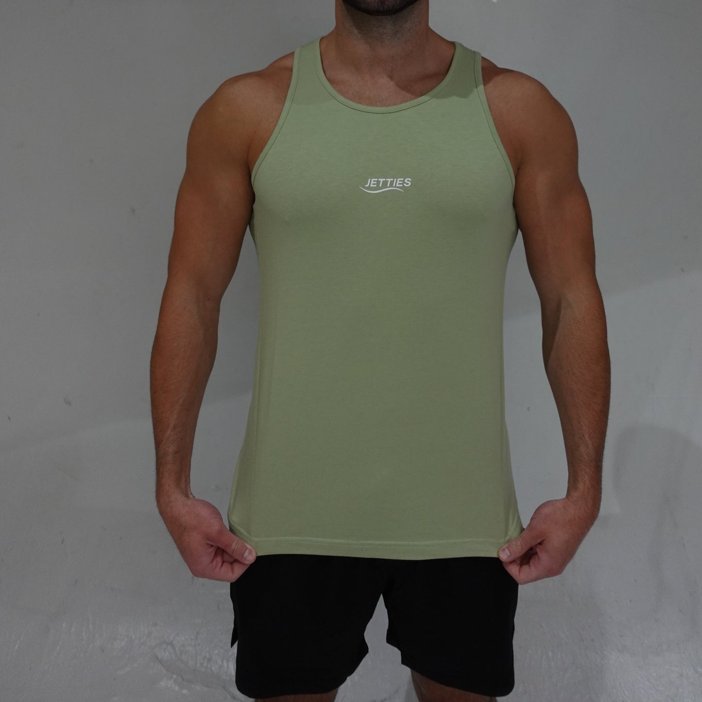 JETTIES Ascend Tank Top in matcha green, lightweight athletic tank with logo graphic, front view