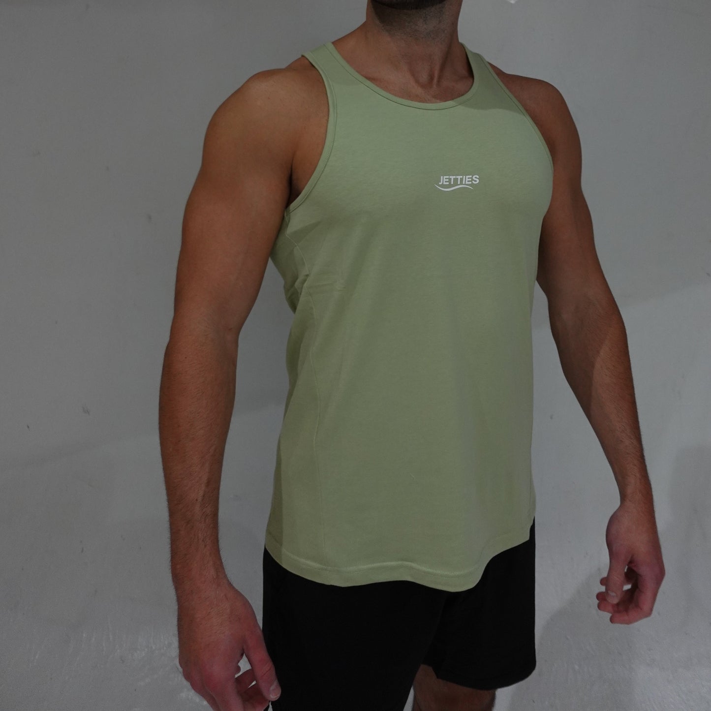 JETTIES Ascend Tank Top in matcha green, lightweight athletic tank with logo graphic, side view