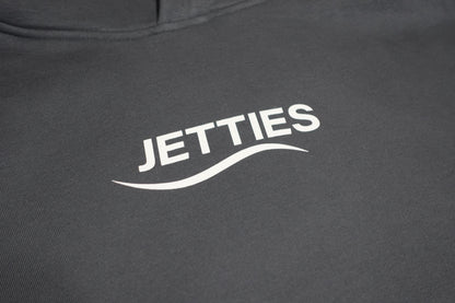 Close-up shot of the JETTIES chest logo printed in white on the gray hoodie.