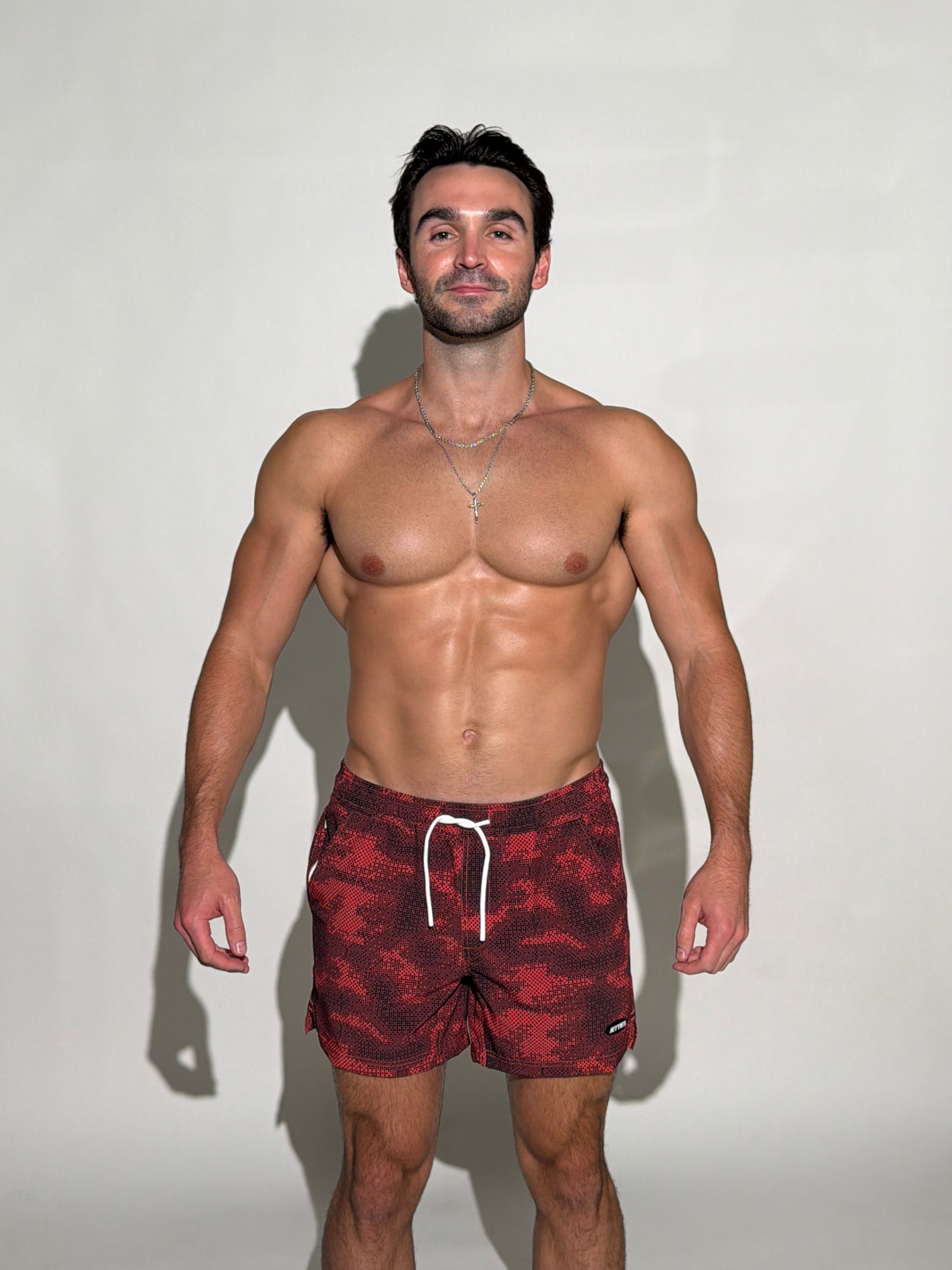 Model wearing the Shadow, black and red digital pixel camo mens bathing suit