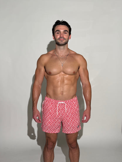 Model wearing the JETTIES Delta Red, red and white triangle mens bathing suit, geometric pattern