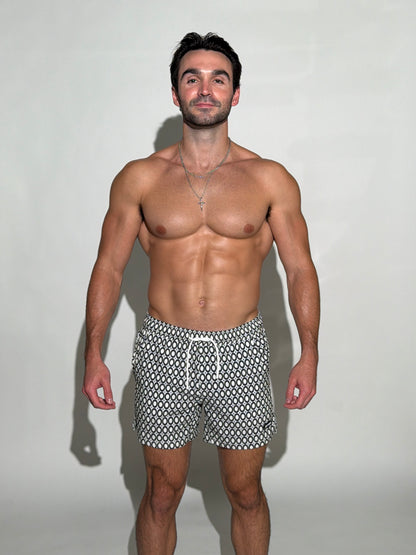Model wearing the JETTIES Echo Charcoal, black and white circles mens bathing suit, geometric pattern