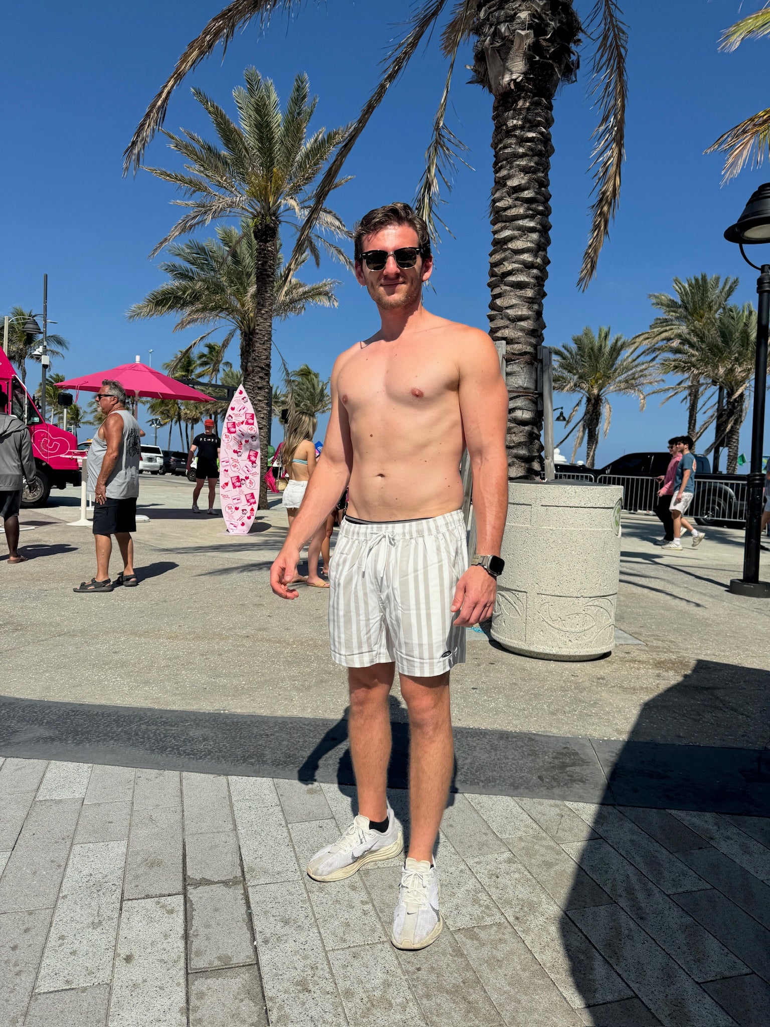 Model standing at beach on a sunny day wearing JETTIES CODE GRAY PLUNGE SHORT bathing suit
