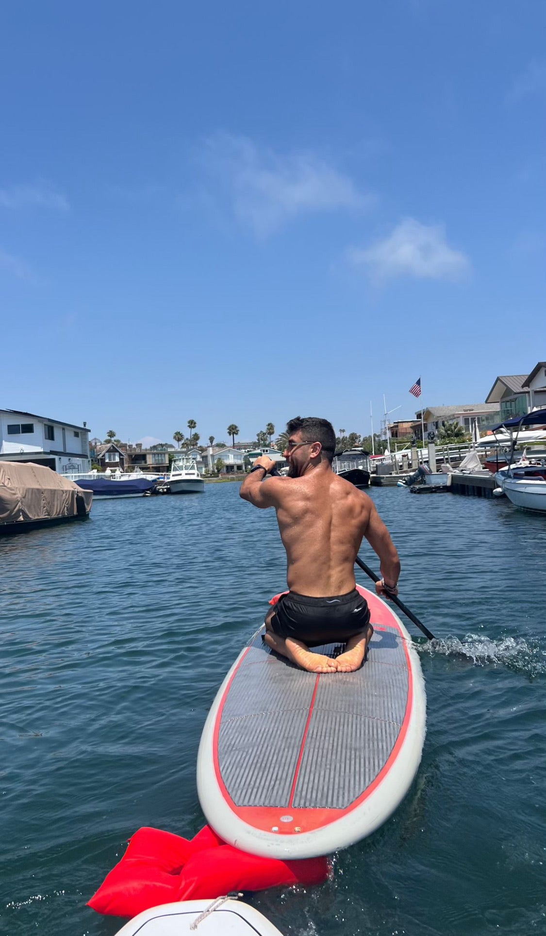 Model paddleboarding in JETTIES CLASSIC BLACK PLUNGE SHORT bathing suit out on a river