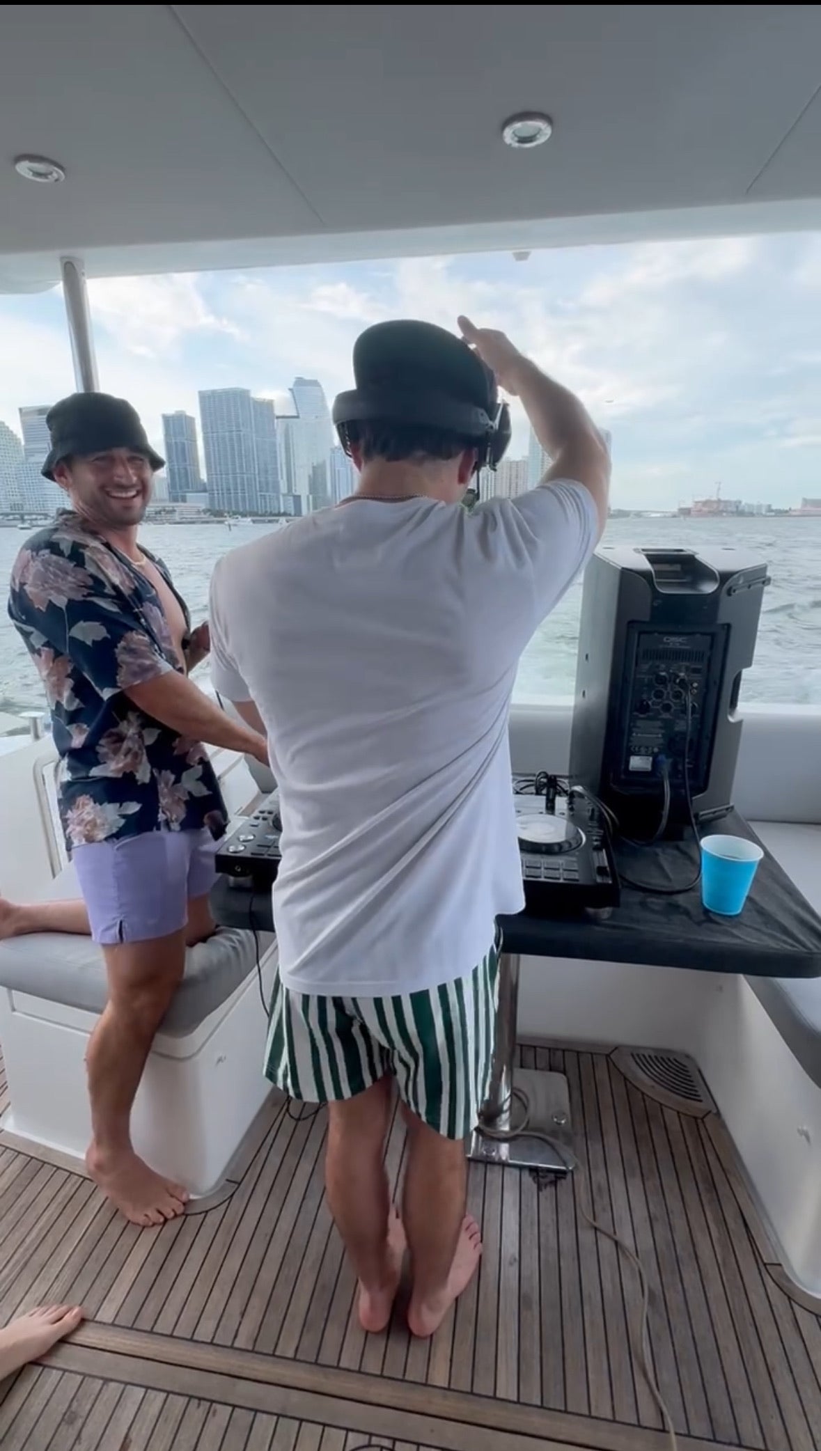 Two friends on a boat in JETTIES LAVENDER WAVE & CODE GREEN PLUNGE SHORTS partying